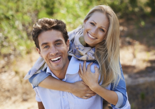 Smiling man and woman holding each other outdoors